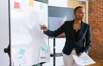 una empresaria está explicando unas gráficas en una pizarra