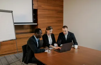 Tres trabajadores están en la oficina mirando el ordenador