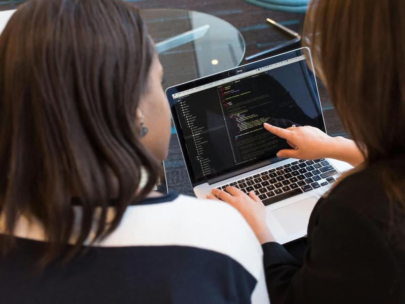 dos compañeras de trabajo están viendo códigos de programación en el ordenador