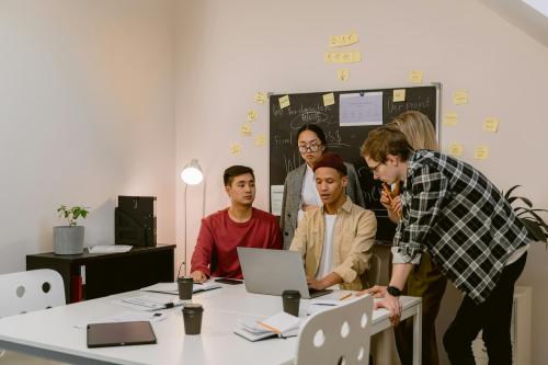 Un grupo de jóvenes están en una oficina viendo el ordenador de su compañero 